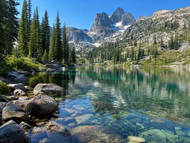 Editorial image of a clear alpine lake with a rocky mountain shoreline