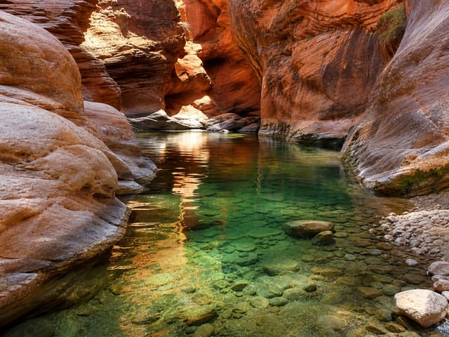 Editorial image of a desert canyon pool framed by red sandstone walls