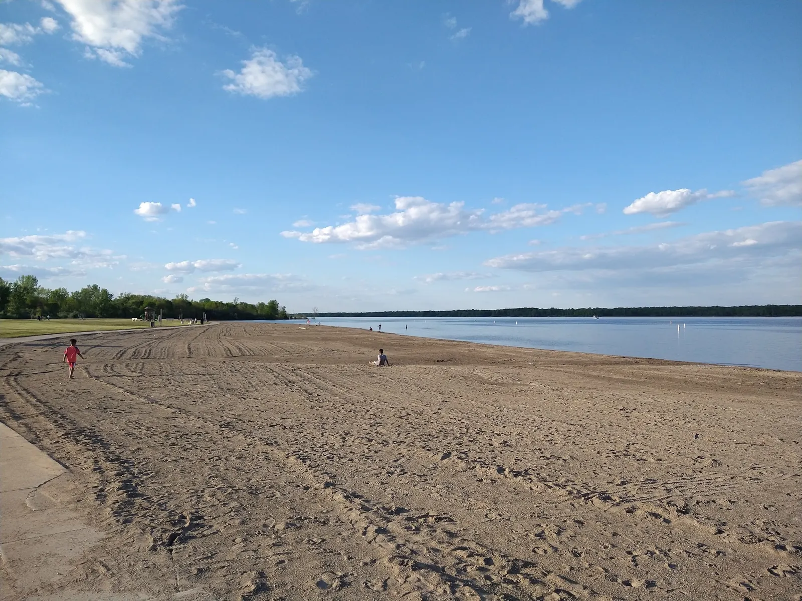 Wide sandy swimming beach beside Alum Creek Reservoir with a paved path along the grass