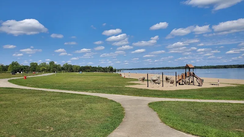 Curving paved paths, grassy picnic area and playground beside the sandy beach at Alum Creek State Park
