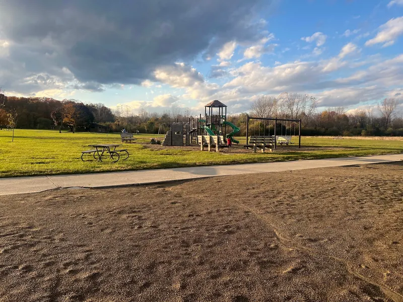 Playground, picnic table and paved path beside the sandy beach at Alum Creek State Park