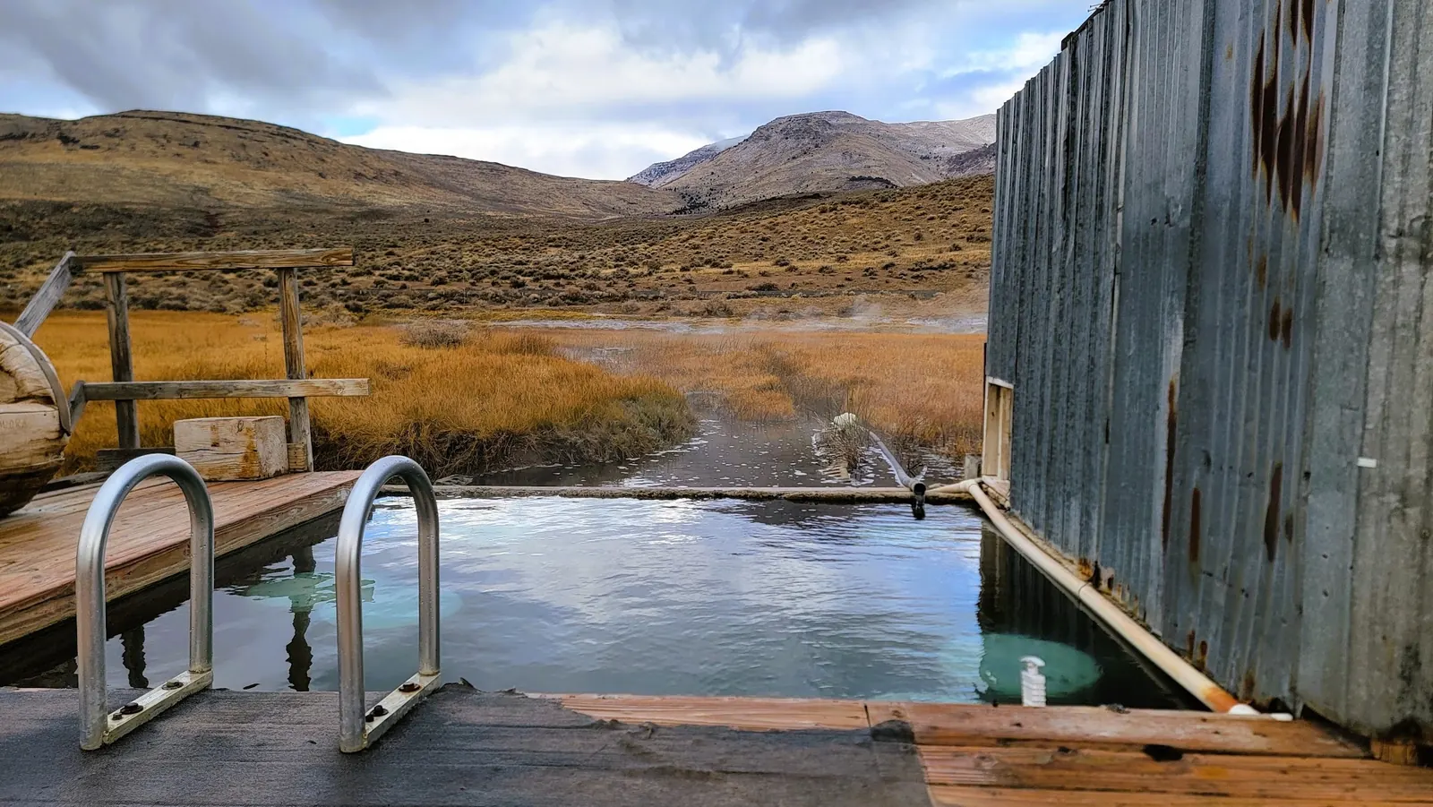 Outdoor soaking pool with entry rails and mountain views at Alvord Hot Springs