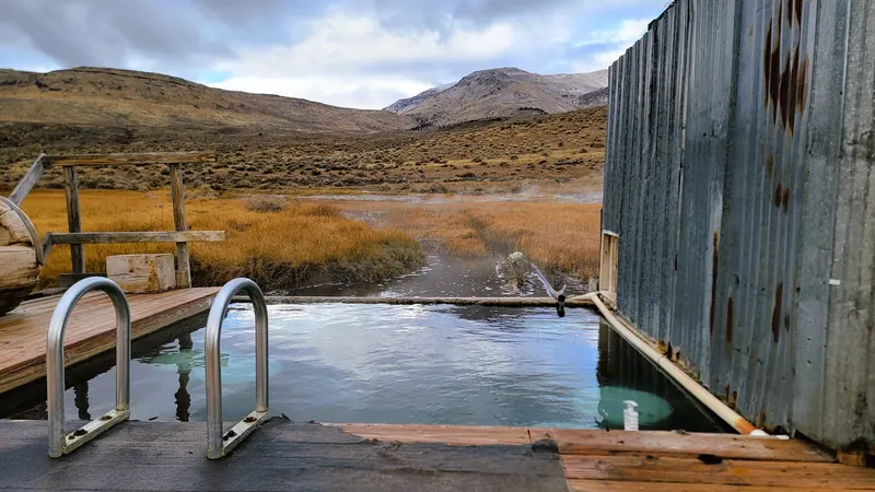 Outdoor soaking pool with entry rails and mountain views at Alvord Hot Springs