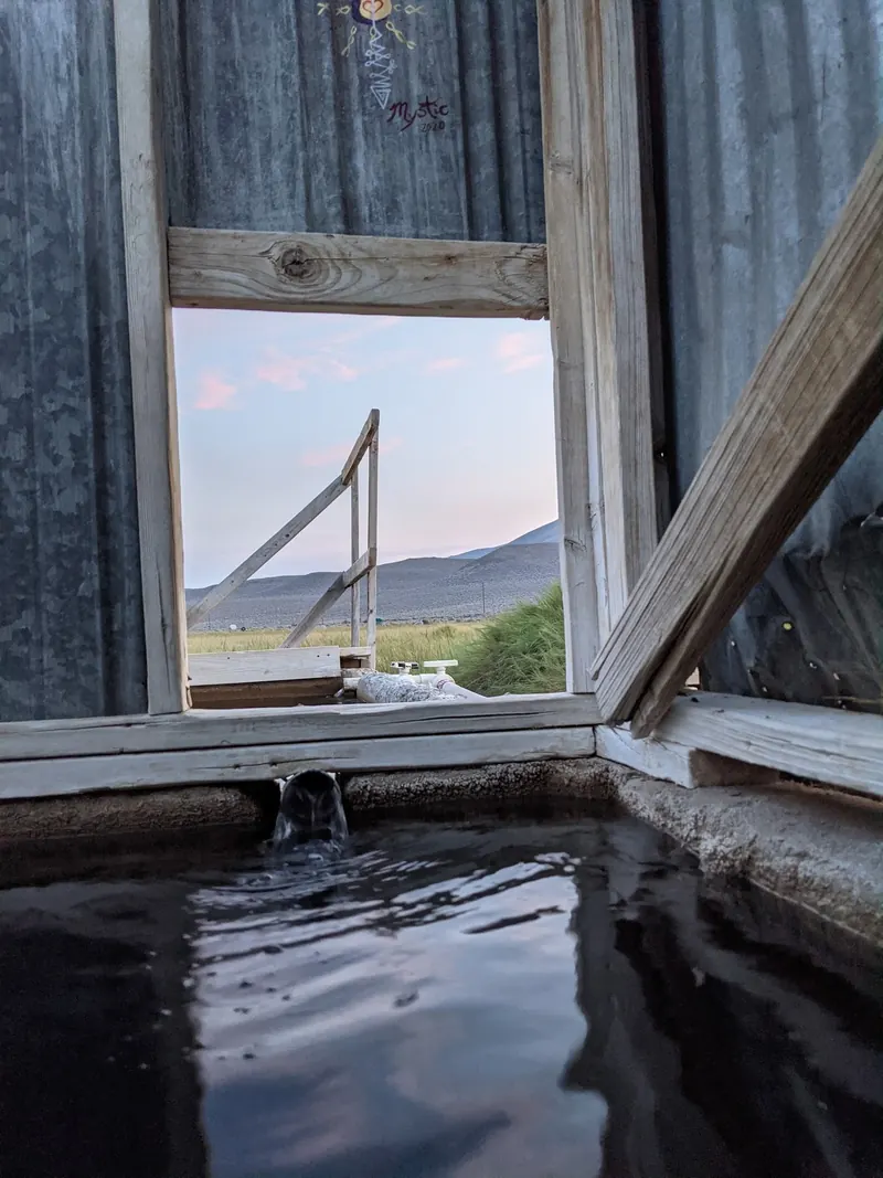 Water inlet and wood-framed opening in a corrugated bathhouse in the Alvord Hot Springs collection; historical interior detail