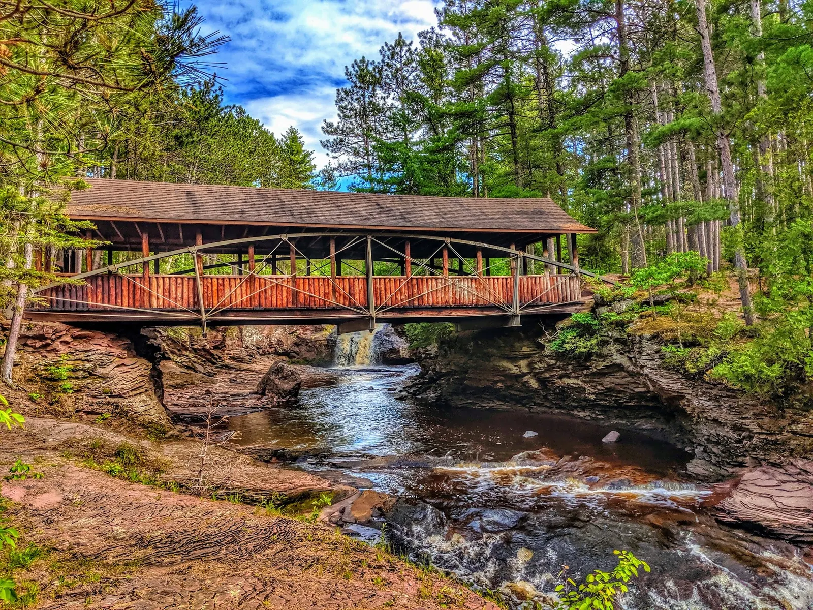 Covered wooden bridge spanning the rocky river at Amnicon Falls State Park