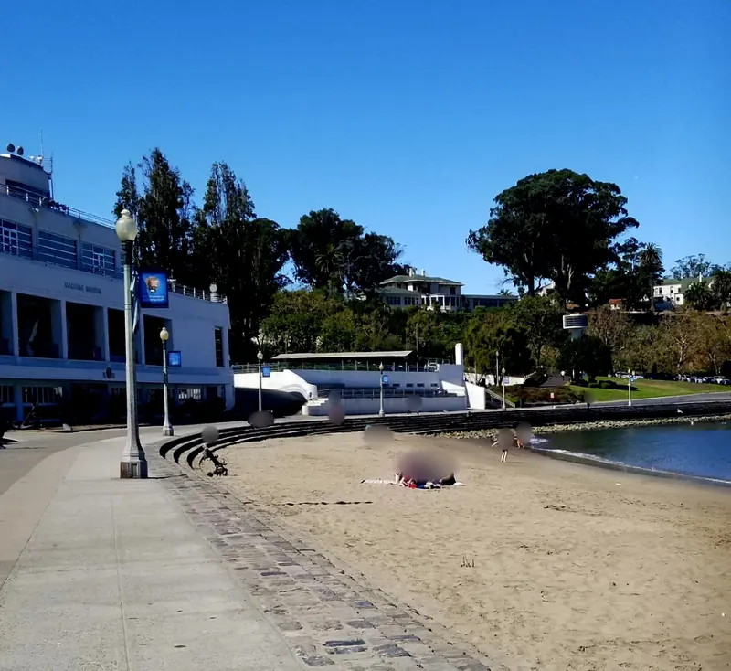 Historic view of the Maritime Museum building, curved waterfront steps and sandy beach at Aquatic Park; not current access or water conditions