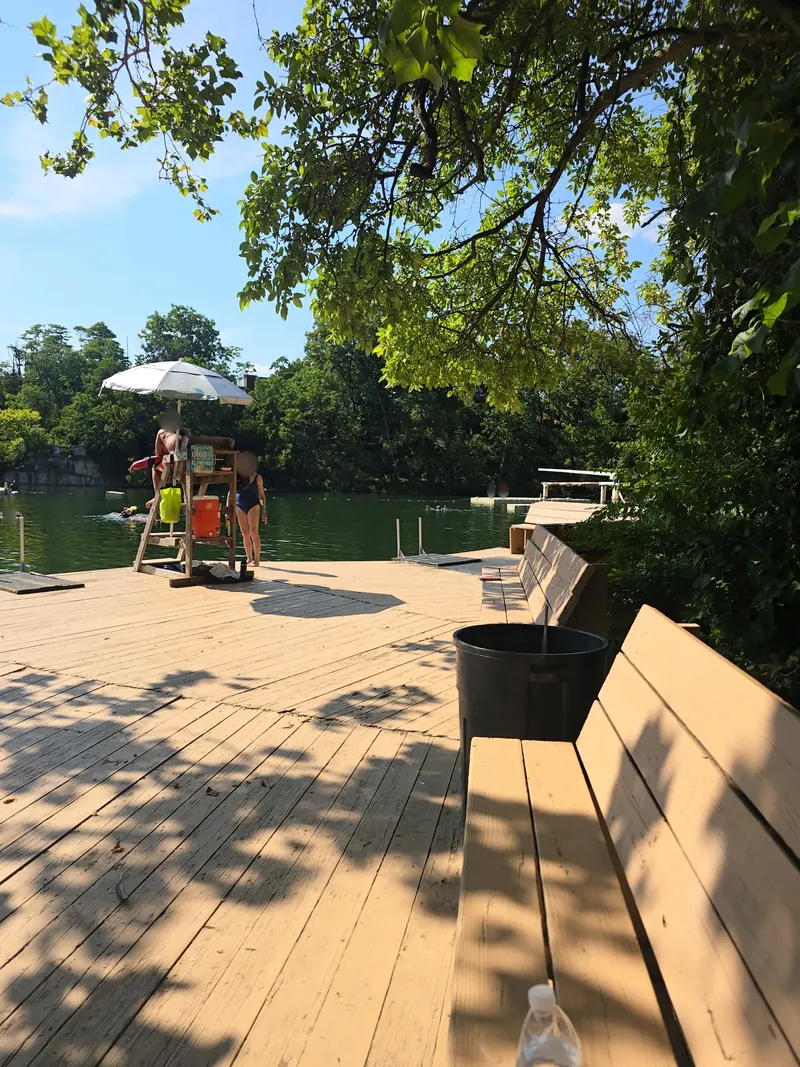 Shaded benches and a lifeguard chair on the quarry deck at Beaver Dam Swimming Club