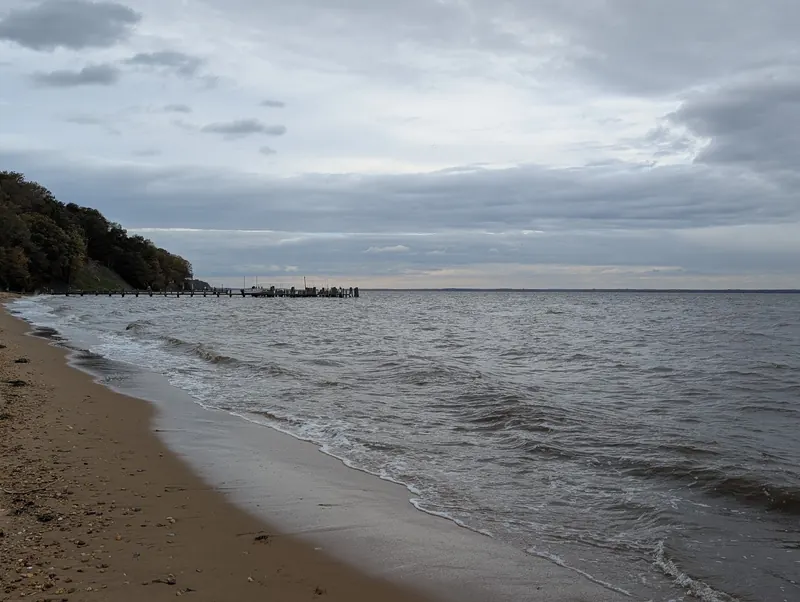 Waves along the sandy shoreline at Betterton Beach with piers in the distance