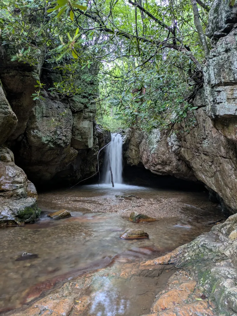 Narrow waterfall between tall rock walls and overhanging branches in the Elizabethton Blue Hole photo collection