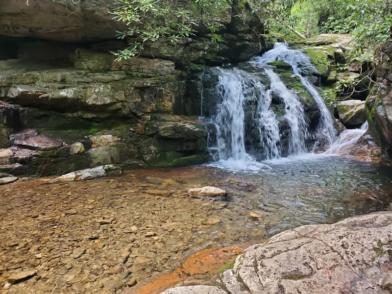 Low cascade spilling over mossy rock into a shallow-looking creek basin in the Elizabethton Blue Hole collection