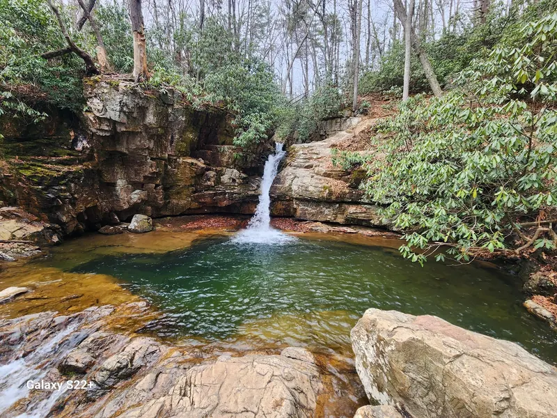 Waterfall descending between layered rock walls into a broad pool in the Elizabethton Blue Hole collection