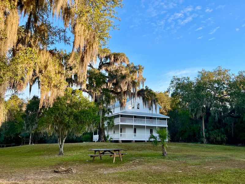 White historic house and picnic table beneath moss-draped trees at Blue Spring State Park