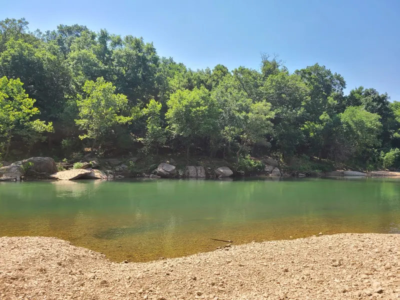 Gravel shoreline facing a wooded rock bank in the Boy Scout Hole creek photo collection