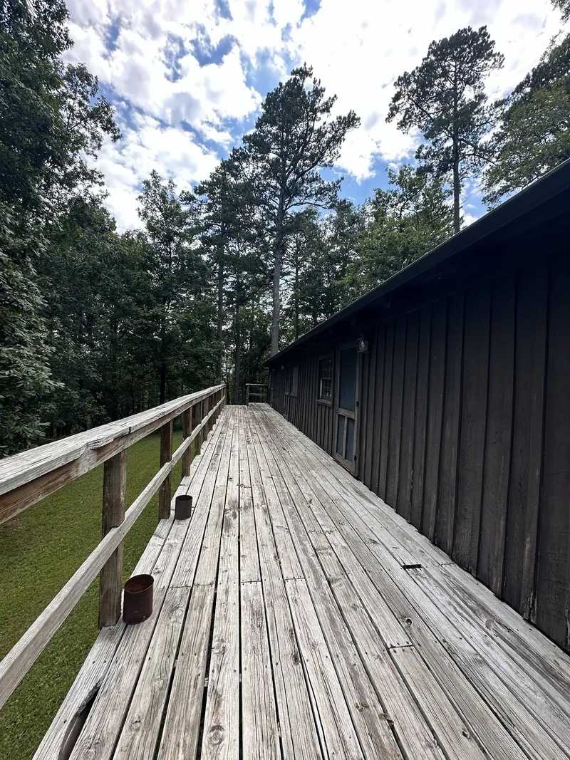 Wooden deck and railing beside a dark-sided building among trees in the Buffalo Point lodging photo collection; not a beach approach