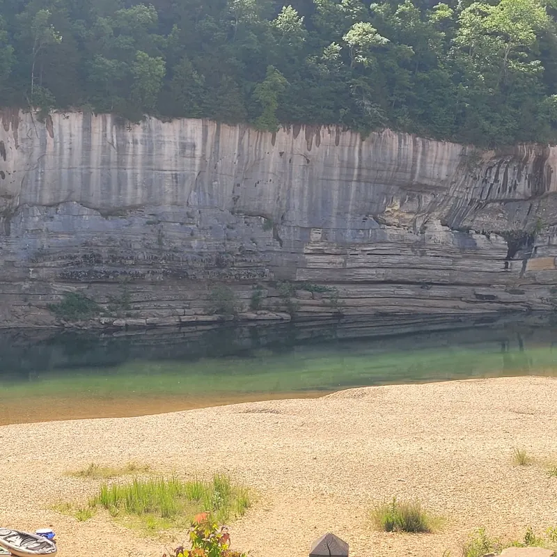 Gravel riverbank and a tall streaked bluff at Buffalo Point
