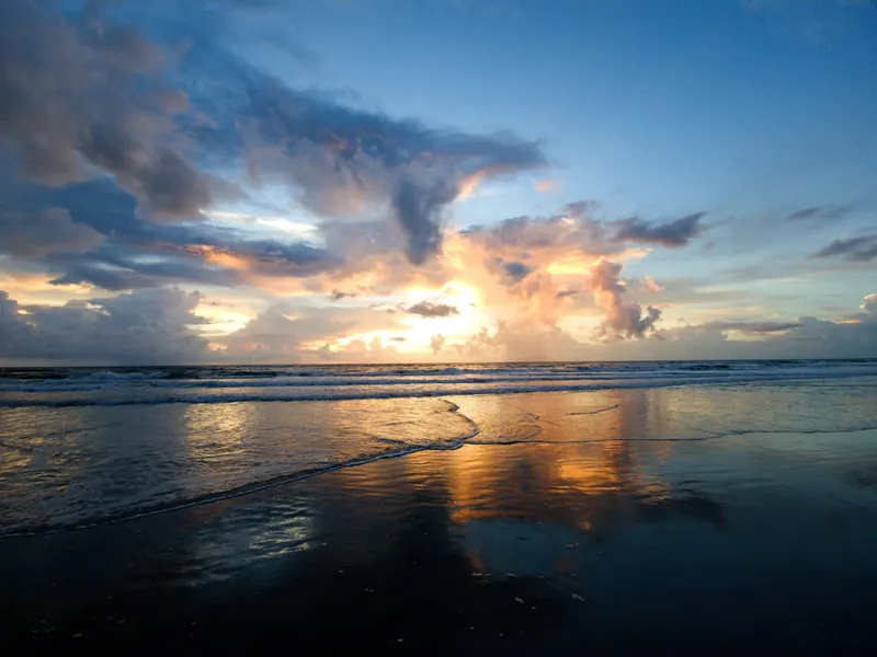 Golden light reflected on wet sand beneath clouds and breaking waves in the Canaveral National Seashore collection