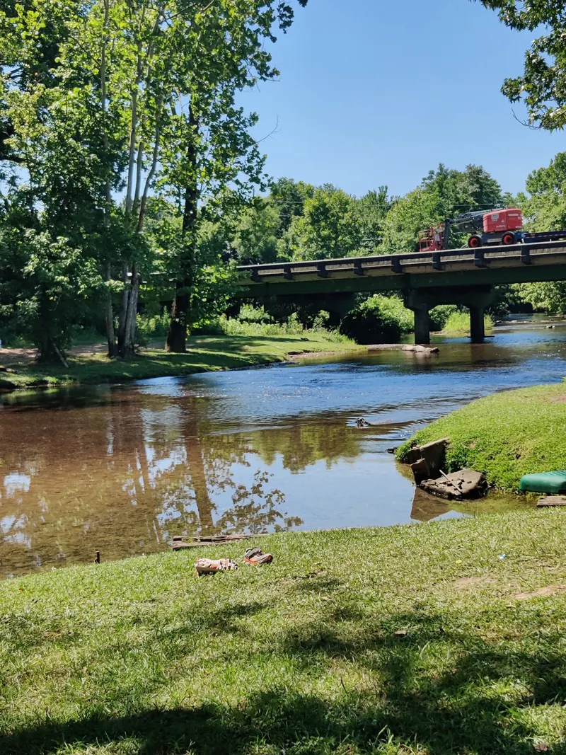 Coldwater Creek flowing beneath the highway bridge beside grassy banks near Oxford, Alabama