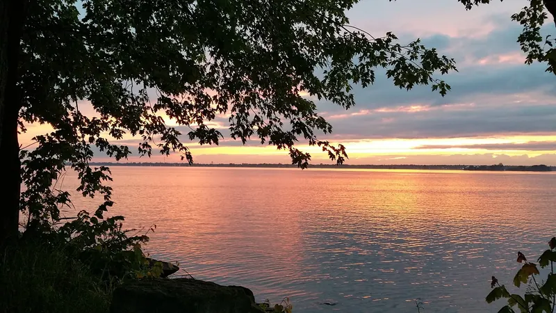 Sunset over the St. Lawrence waterfront framed by leaves at Coles Creek State Park