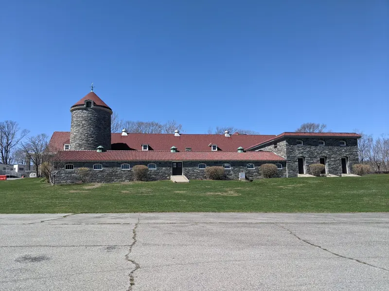 Stone building with a round tower and red roof at Colt State Park