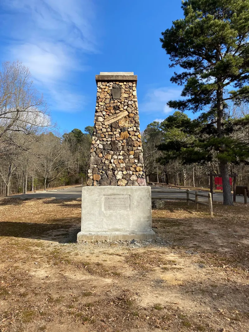 Stone Benjamin Crowley monument beside a wooded park path