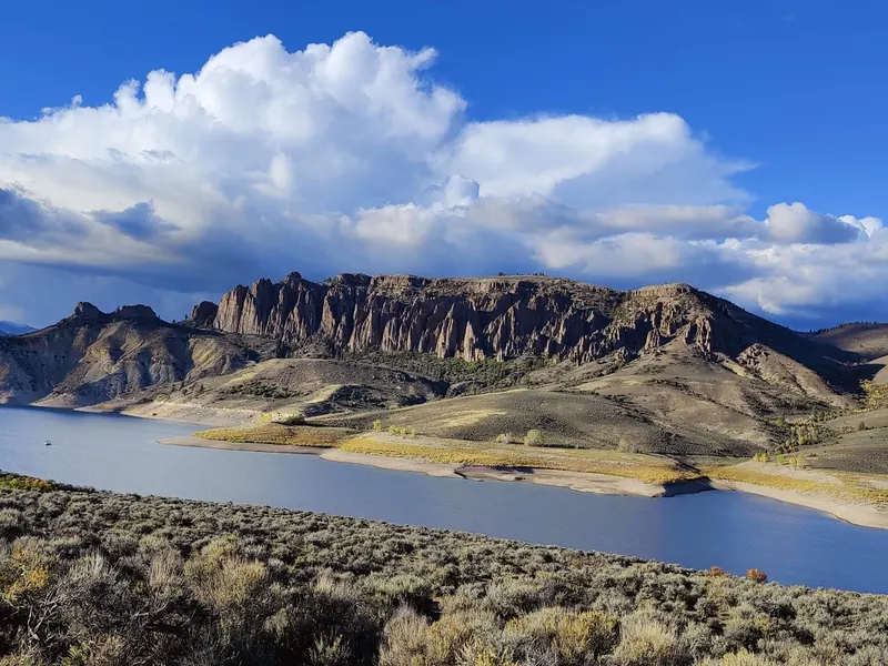 Blue Mesa Reservoir below rugged rock pinnacles and sage-covered slopes in Curecanti