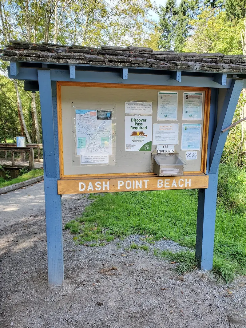 Dash Point Beach information board with a state park map and historical Discover Pass notices