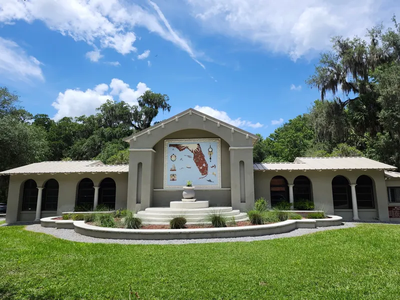 Arched park building with a Florida map mural and landscaped lawn at De Leon Springs State Park