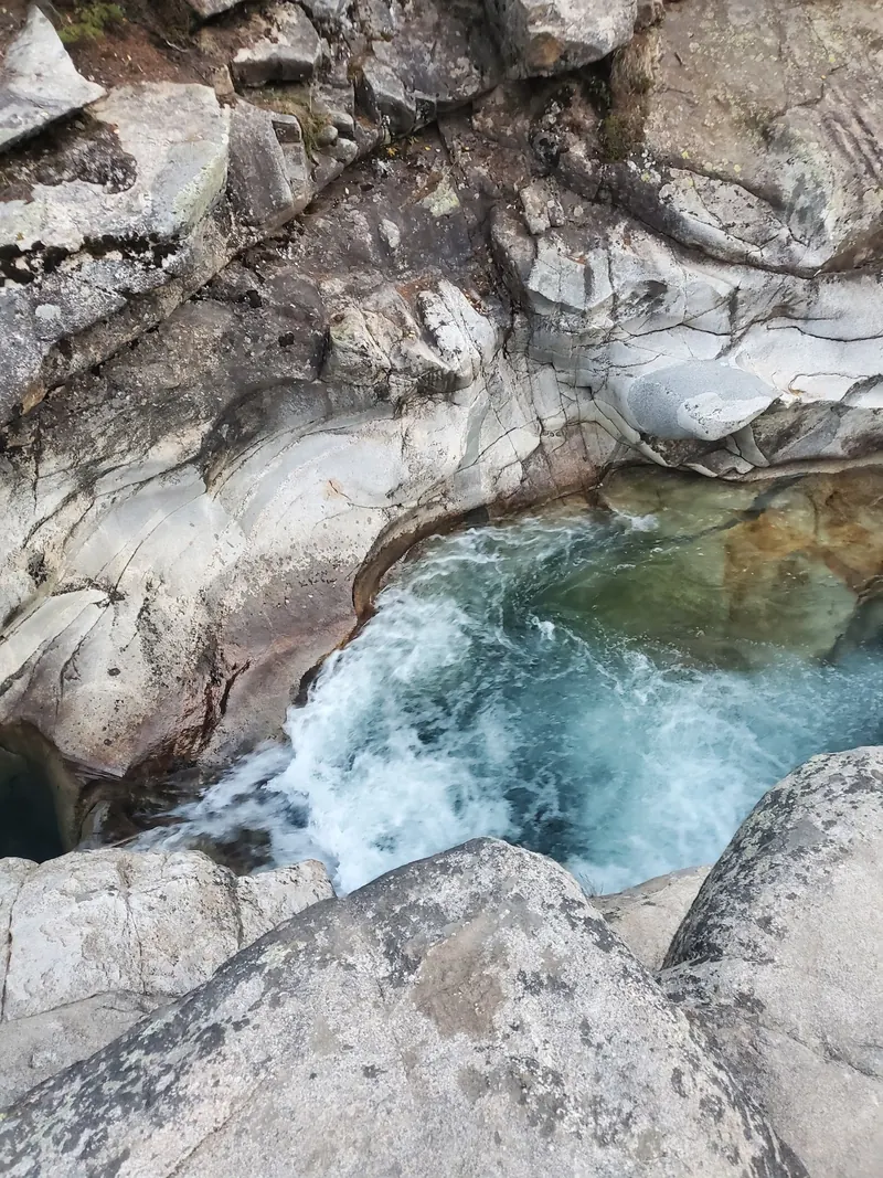 Close view of blue water and whitewater flowing through a rounded rock channel
