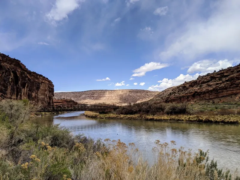 River and metal truss bridge between rocky canyon walls in the Dominguez Canyon area