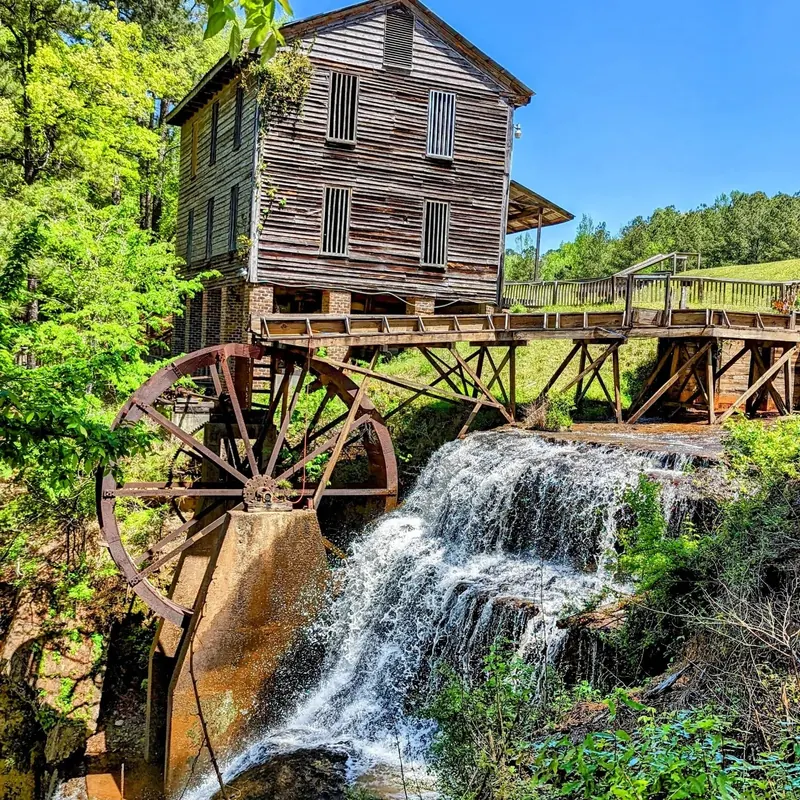 Historic wooden mill and large water wheel beside the waterfall at Dunn's Falls Water Park