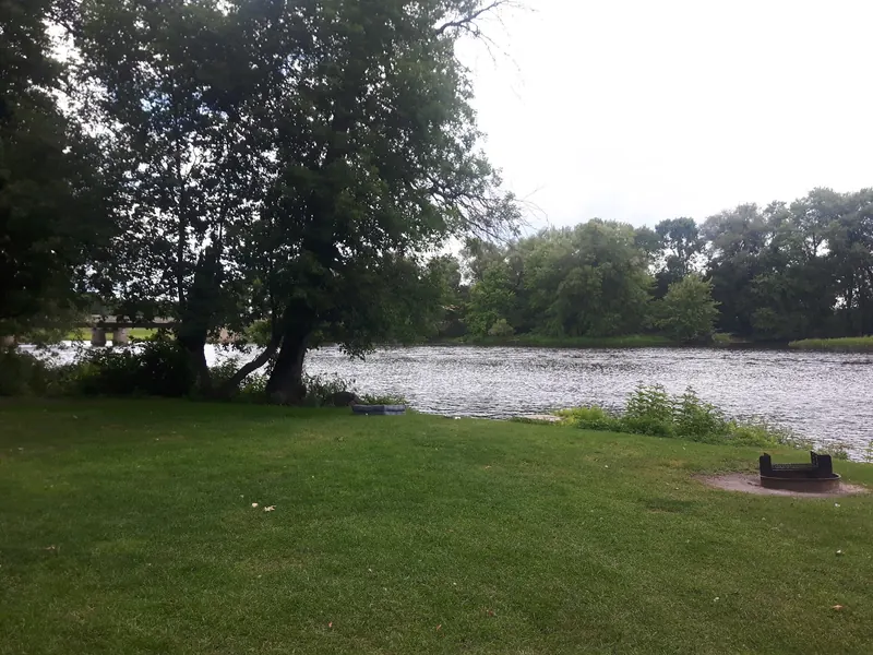 Grassy riverside campsite and fire ring at Eel Weir State Park, not a verified swimming entry