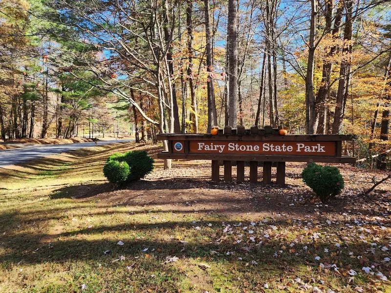 Fairy Stone State Park entrance sign beside the wooded park road in autumn