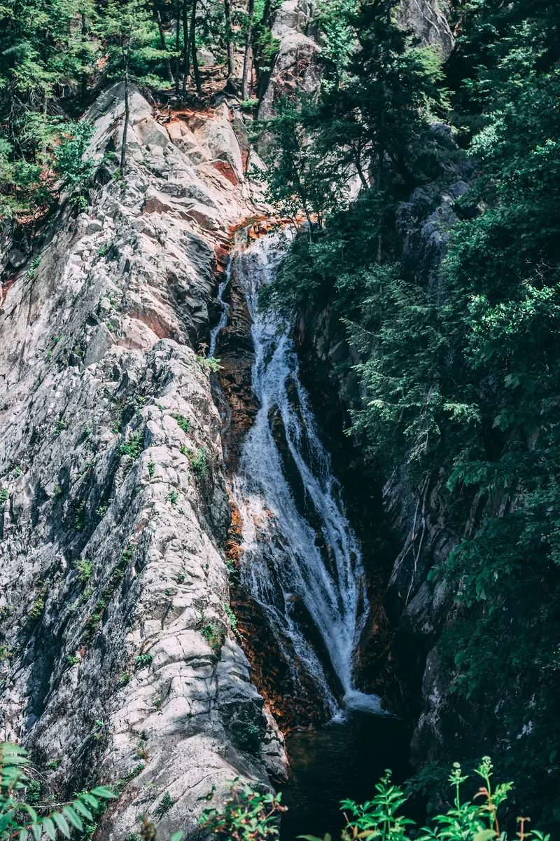 Falls of Lana descending between steep rock walls surrounded by green forest