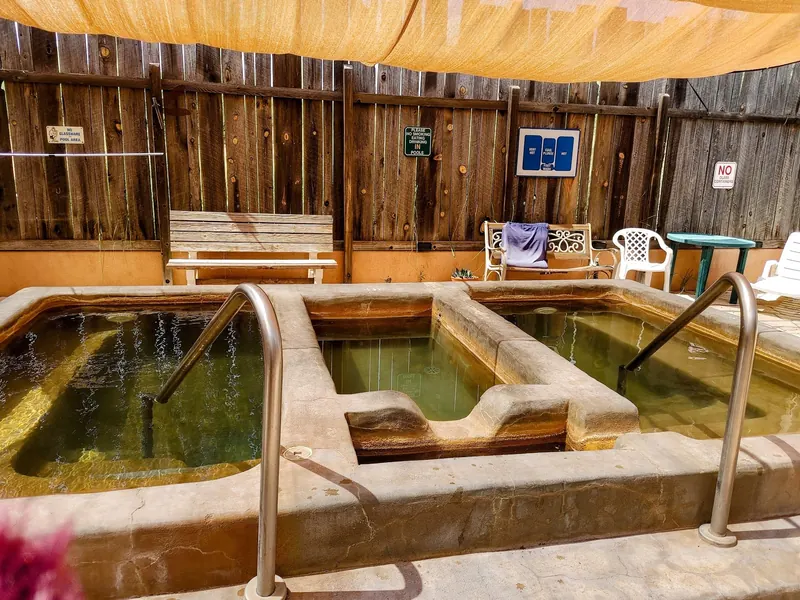 Adjacent empty soaking pools beneath shade fabric at Faywood Hot Springs