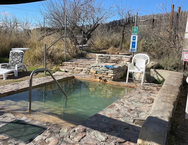 Empty stone-edged soaking pool with steps and handrails at Faywood Hot Springs