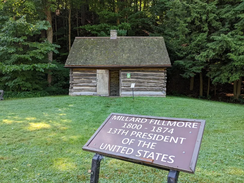 Replica log cabin and Millard Fillmore interpretive sign at Fillmore Glen State Park