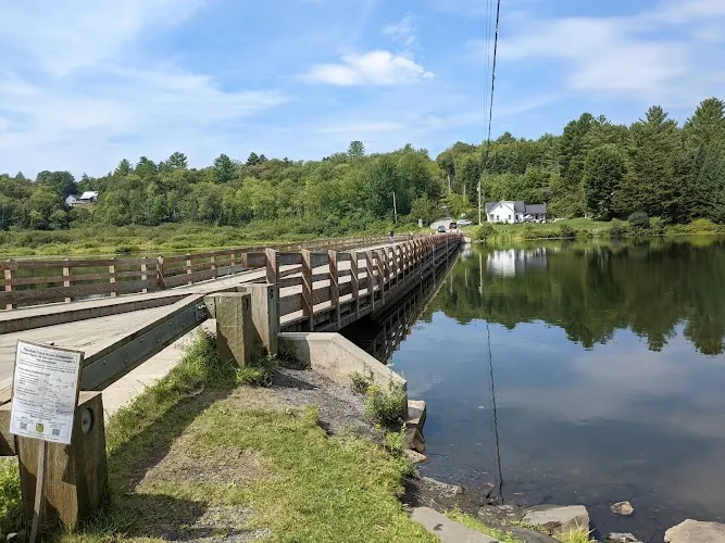 Wooden Brookfield Floating Bridge across Sunset Lake with a foreground information board; historical landmark view, not a swimming entrance