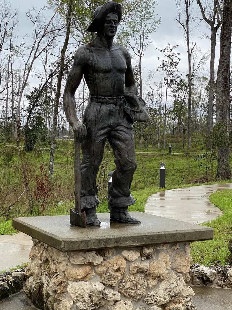 Historical view of a worker statue holding a shovel beside a paved path at Florida Caverns State Park; park context, not Blue Hole swimming access