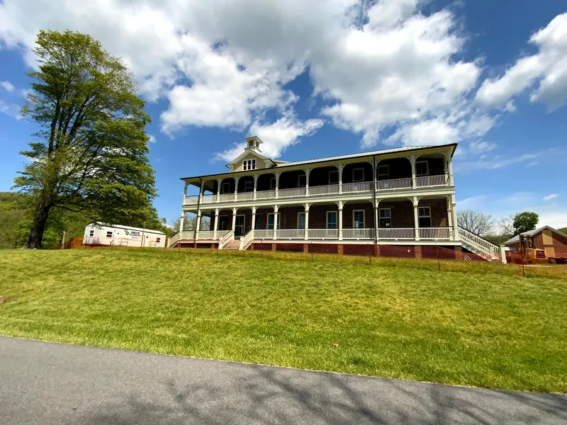 Historic view of the Inn at Foster Falls with its two-story porch and construction equipment; source dated 2020