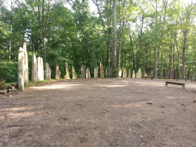Standing-stone circle and wooden benches in a wooded clearing at Four Quarters Interfaith Sanctuary