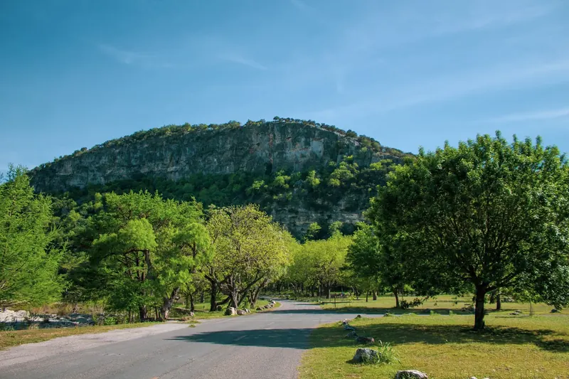 Tree-lined park road below a limestone bluff in the Garner State Park collection