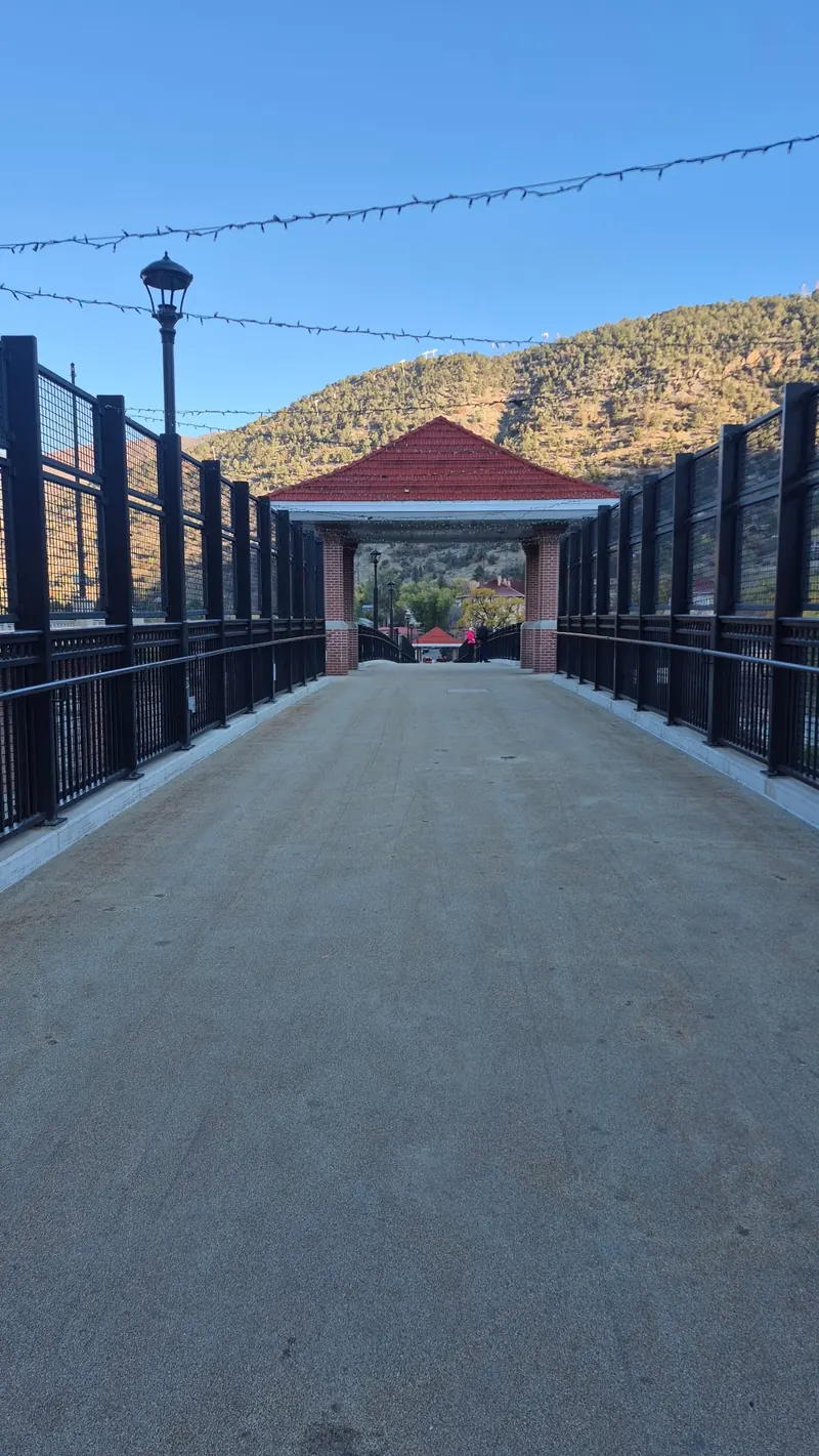 Historical pedestrian bridge with black railings and a red-roofed arch near Glenwood Hot Springs; not an independently verified accessible route
