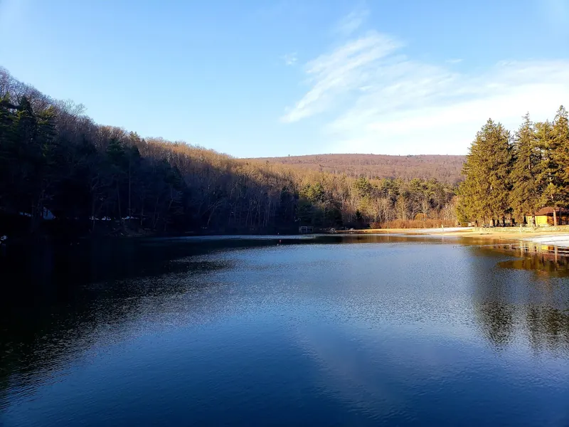 Greenwood Lake and its beach in a past off-season view with leafless trees and snow along the shore