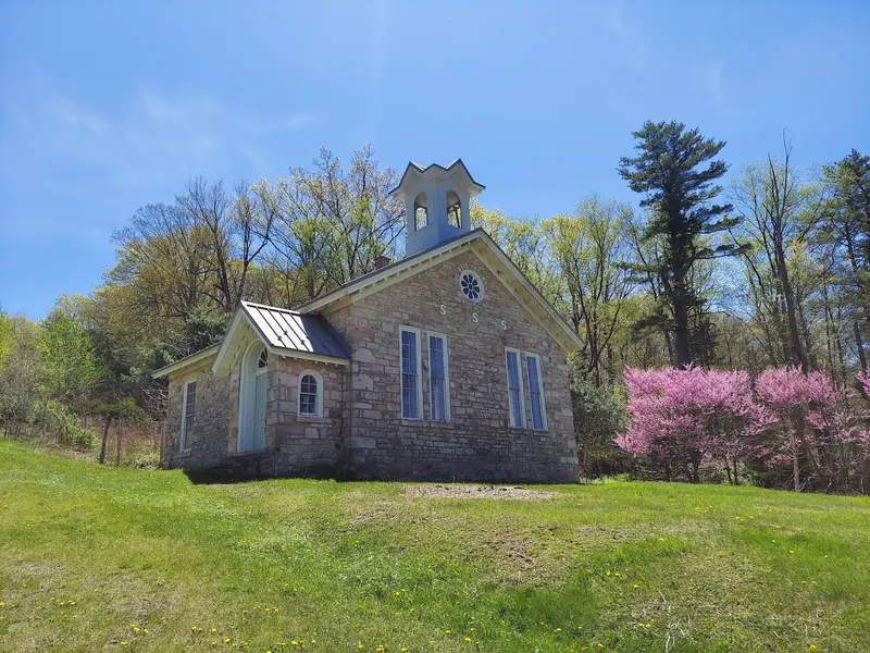 Historic stone church at Greenwood Furnace State Park beside flowering trees