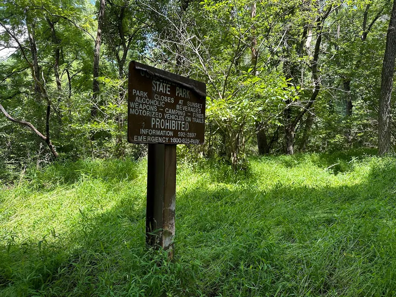 Gunpowder Falls State Park sign among trees listing sunset closing and restrictions in a historical photograph