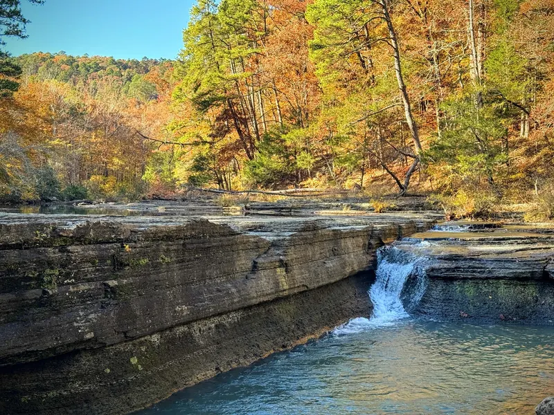 Low waterfall over layered rock at Haw Creek Falls with autumn trees; scenery, not a verified safe water entry