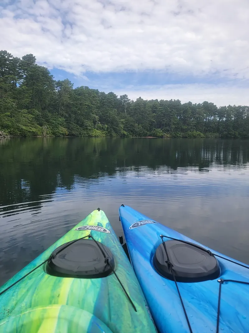 Two empty kayaks beside wooded pond scenery in a historical Hawksnest photo