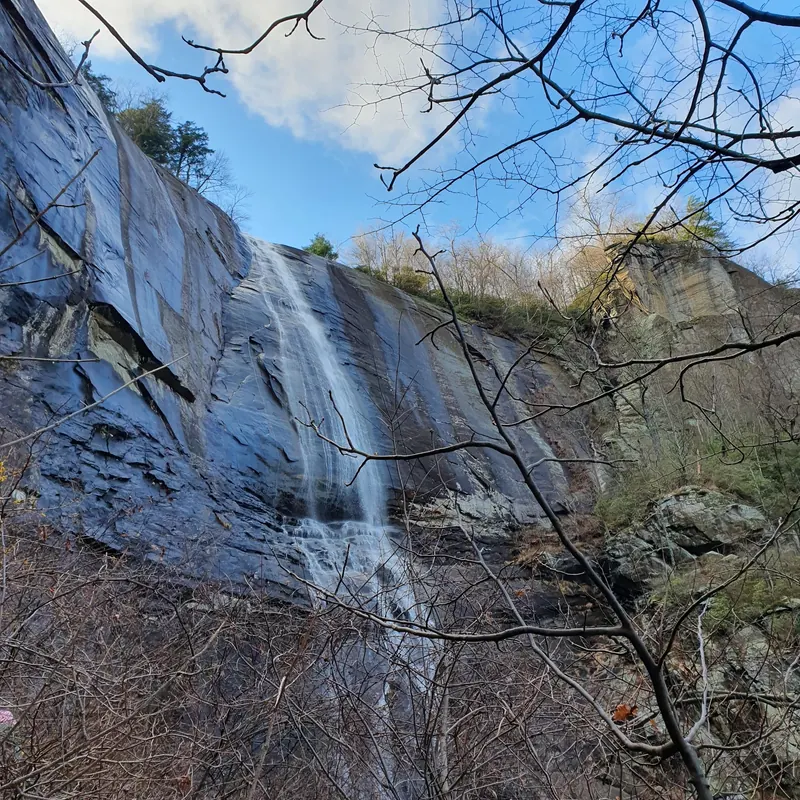 Hickory Nut Falls seen through bare branches against its tall rock wall
