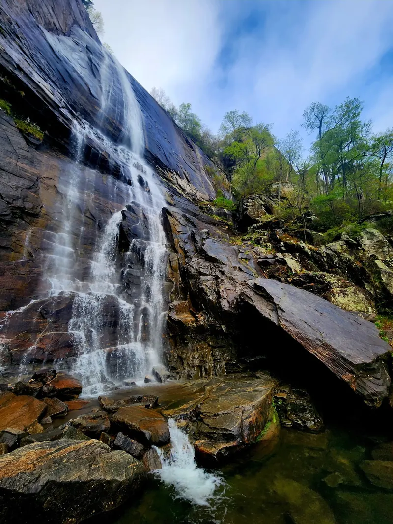 Hickory Nut Falls flowing down a broad rock face beside leafy forest