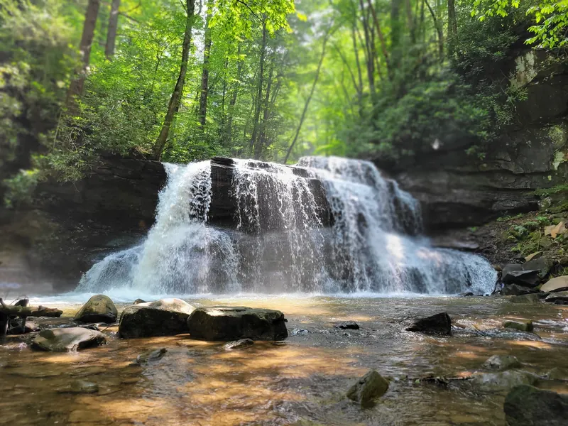 Broad waterfall over layered rock in Holly River State Park; general waterfall scenery, not a verified swimming entry
